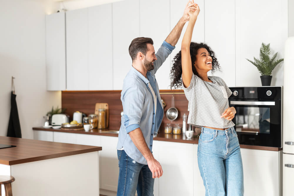 Handsome white man and attractive African American young woman is cooking and having fun together